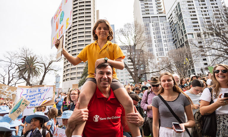 Save the Children CEO Paul Ronalds with a child on his shoulders at the school strike for climate