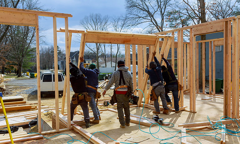 people putting up wooden frame to build a house