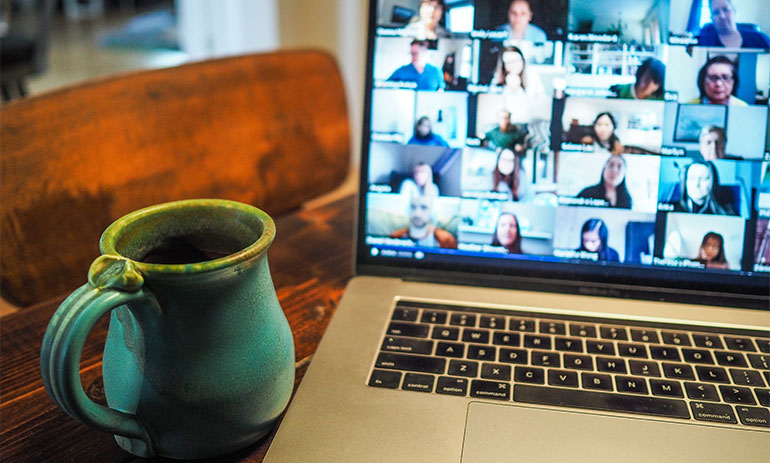 Mug next to laptop with people on screen on zoom meeting