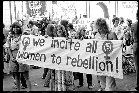 Women taking part in the May Day march in 1974 holding a banner that says "we incite all women to rebellion"