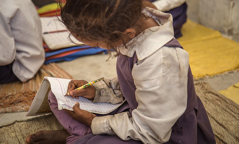 a young girl sitting on the floor doing school work