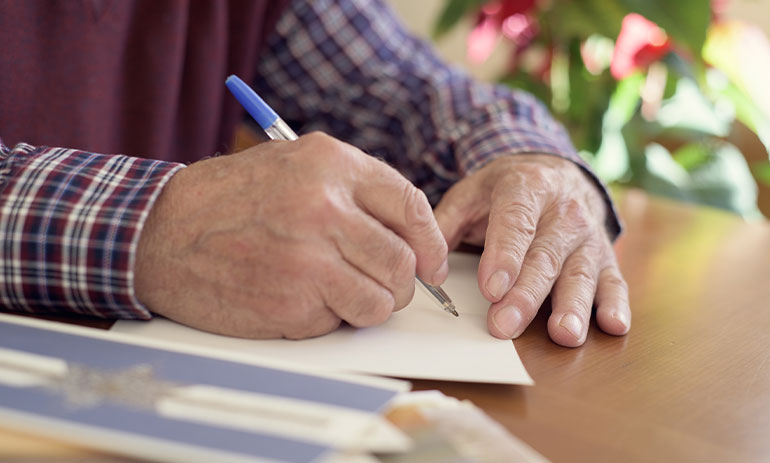 close up man writing a christmas card