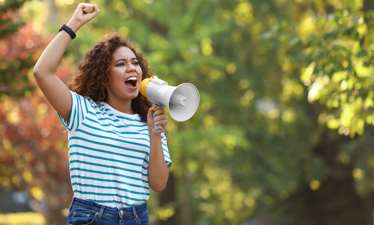 African-American woman with megaphone outdoors.