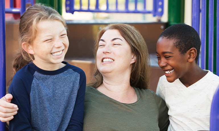 woman with two children all laughing in a park