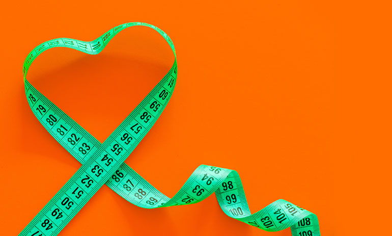 green tape measure in the shape of a heart on an orange background