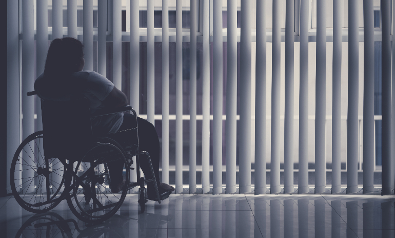 Silhouette of woman sitting in the wheelchair by the window.