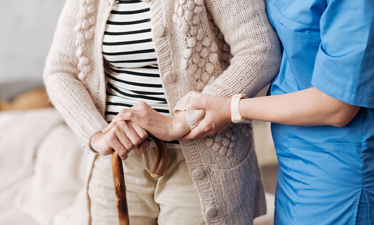 close up image of nurse supporting elderly woman's arm