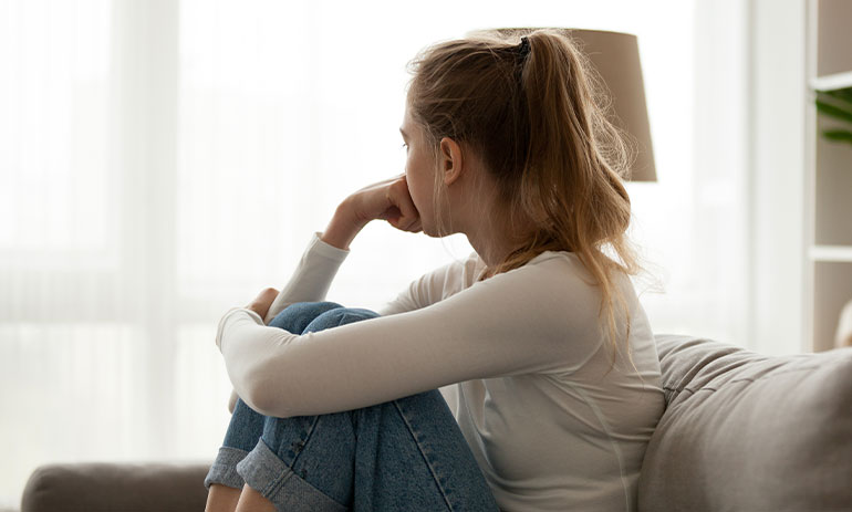 girl sitting on sofa looking away from camera