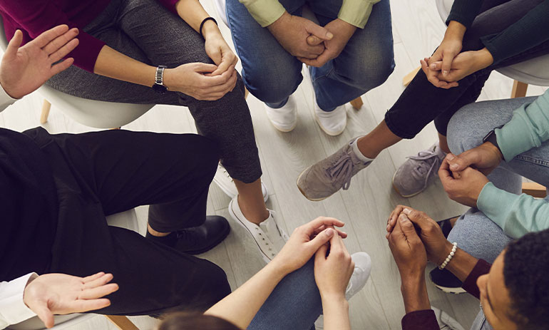 group young people sat in a circle talking to a therapist