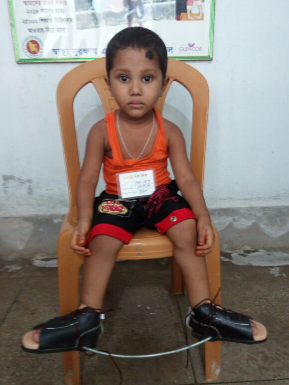 young boy sitting in a chair with his feet turned out