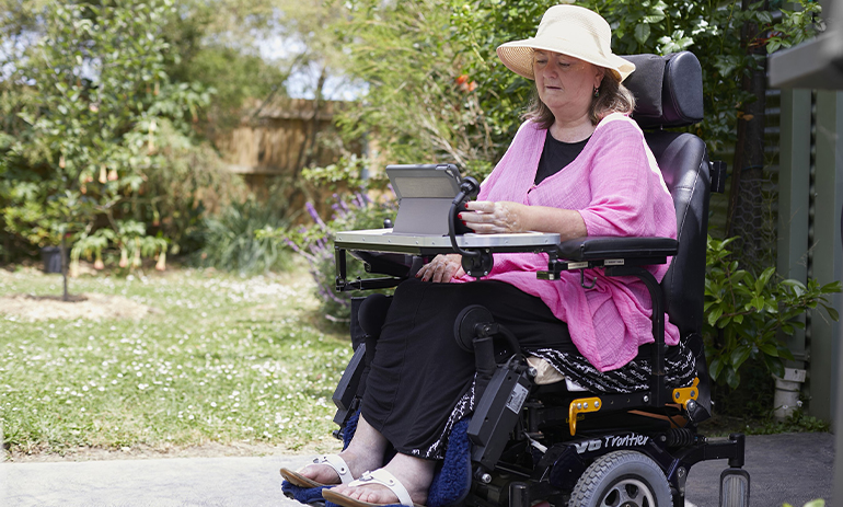MND Victoria client using assistive powered wheelchair and iPad