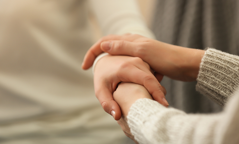 a close up of two pairs of hands clasped in a supportive gesture