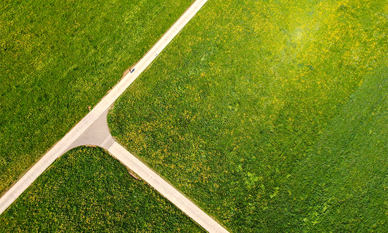 Aerial view of green field with road cutting it in three