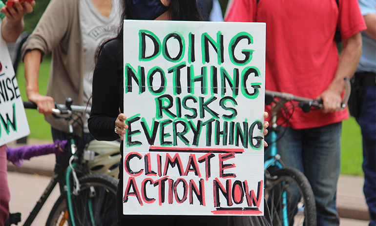 someone is holding a sign that says doing nothing risks everything, climate action now