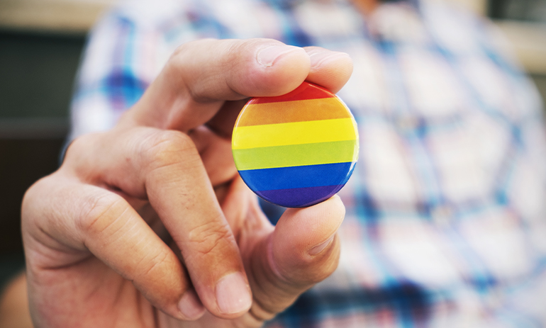 person holding a rainbow badge