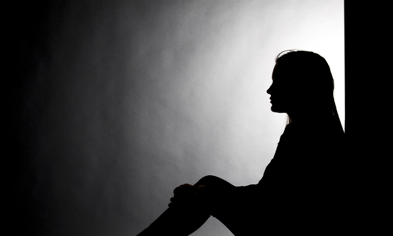 silhouette of woman sat in the dark