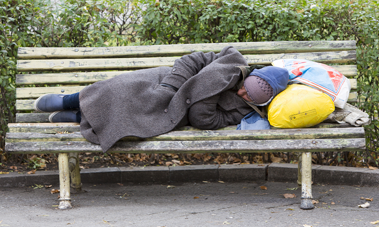 A homeless man sleeping on a bench