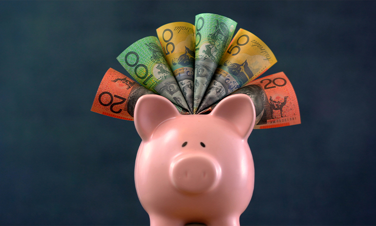 A pink piggy bank stuffed with Australian dollars