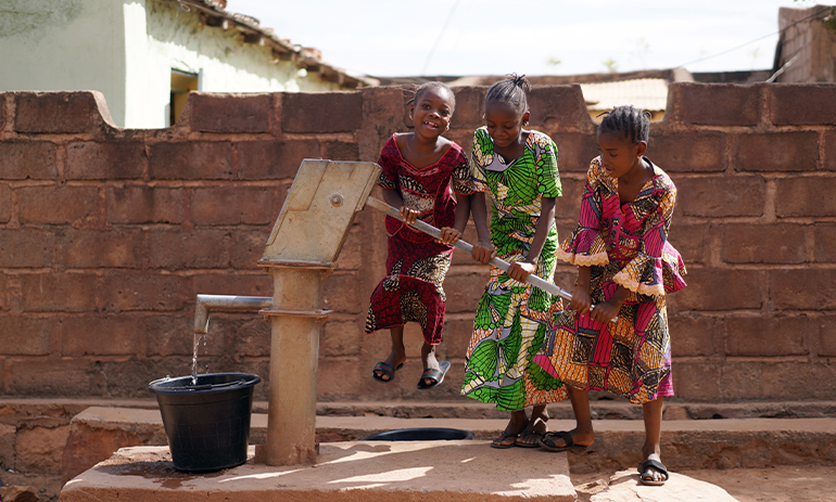 West African Children Filling Up A Water Bucket At The Borehole