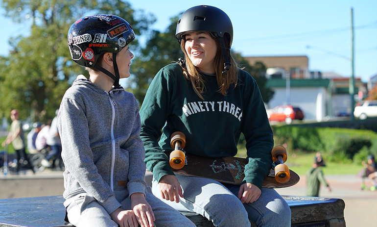 two young people sitting on a skateboarding ramp.