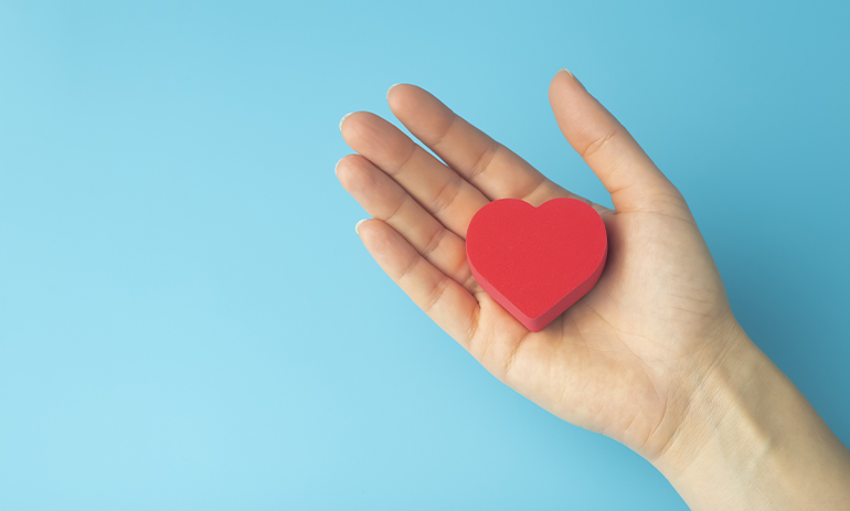 handing holding red heart on a blue background
