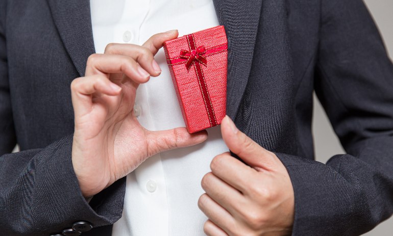 Businessman pulls a gift box out of his suit for giving