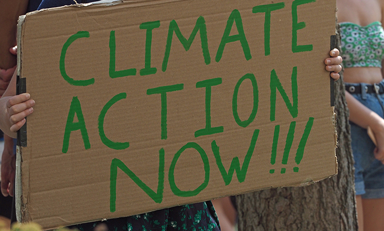 sign at climate protest saying climate action now