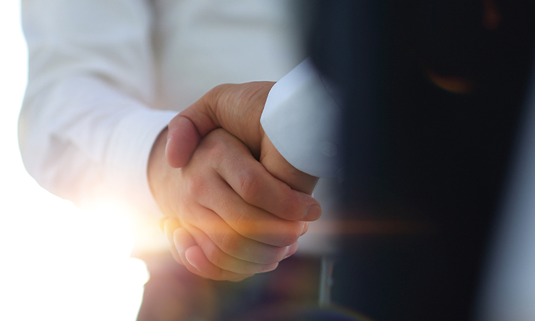 close up of two men in suits shaking hands