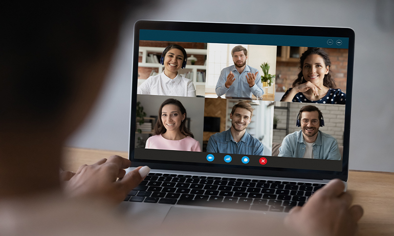Person on video call, laptop screen shows 6 people on it