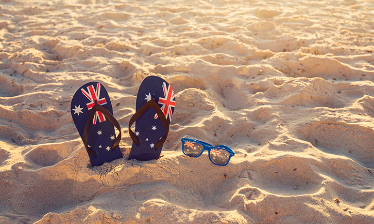 pair of flip flops with Australian flag design and sunglasses on the beach