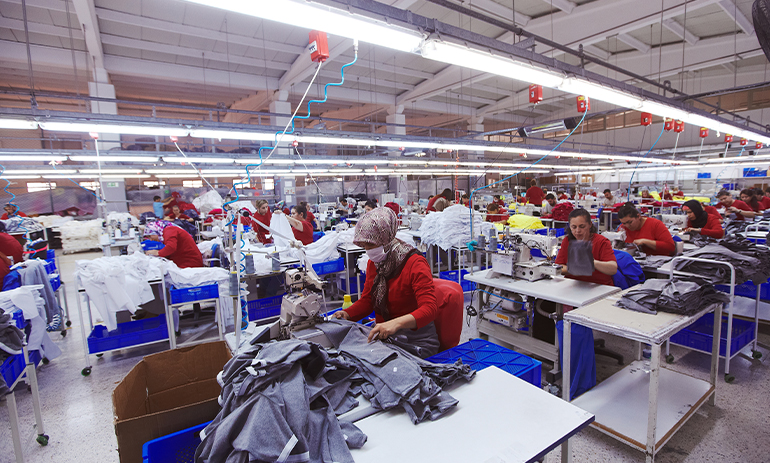 A room full of female machinists sit in a large room and work