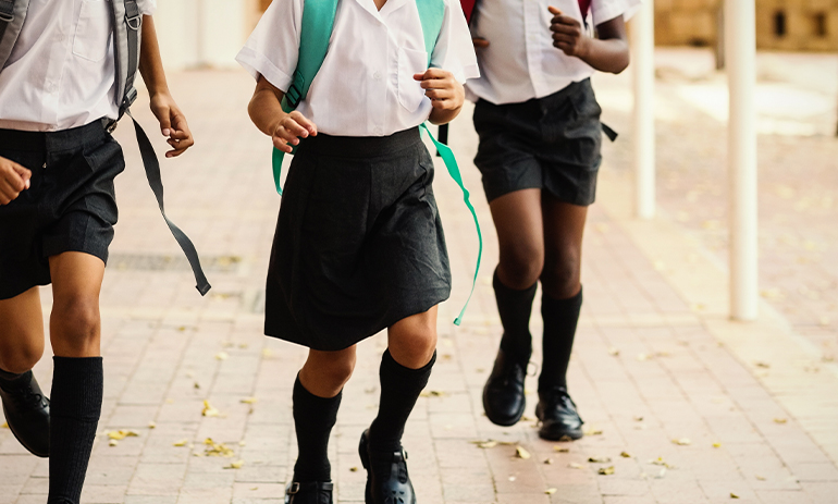 A close up of kids running wearing school uniform