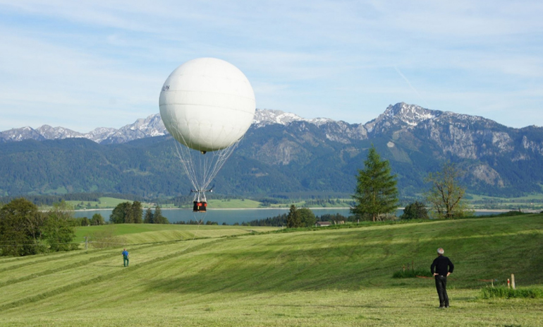 still from documentary Dream On. Yearning for Change, showing a hot air balloon flying with mountains in the background