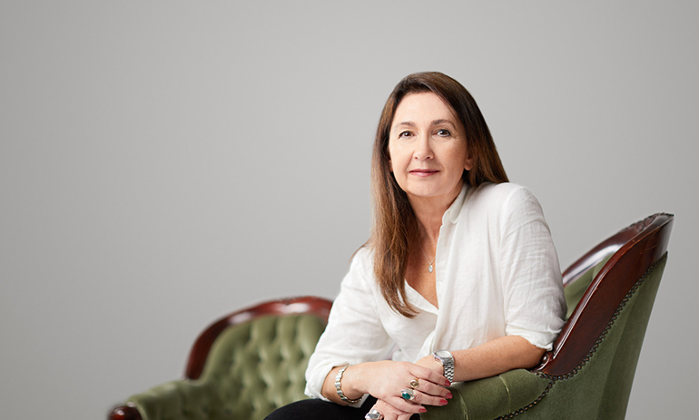Carolyn Butler-Madden wearing a white short sitting on a green sofa