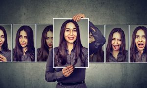 woman with long dark hair in grey shirt holding up different photos of herself showing her in different moods