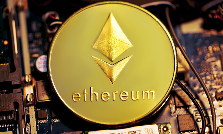 A gold Ethereum coin against a backdrop of a computer motherboard.