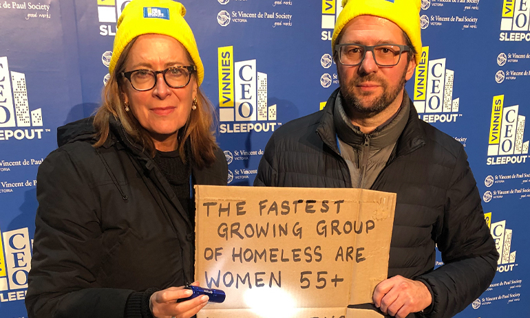 Vedran and Julie hold a cardboard sign saying " the fastest growing group of homeless are women 55+'