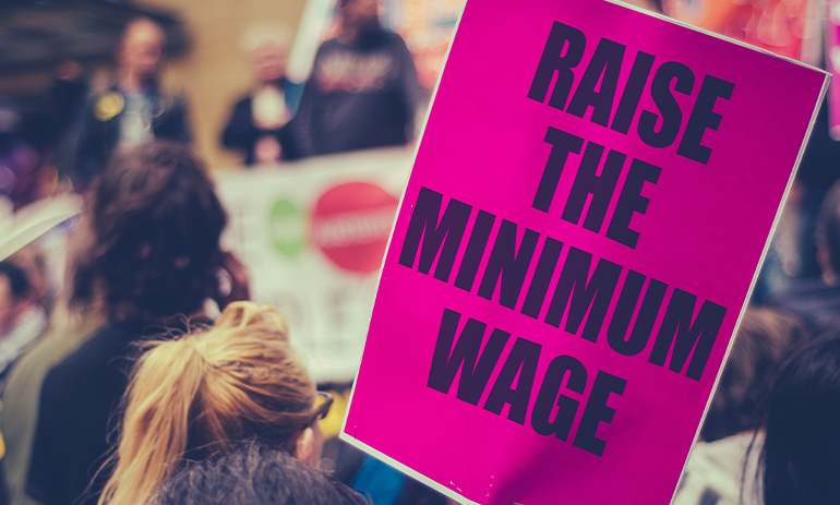 protester holding sign saying raise the minimum wage