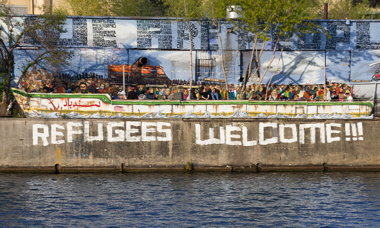 graffiti of a picture of a boat with the words Refugees Welcome underneath