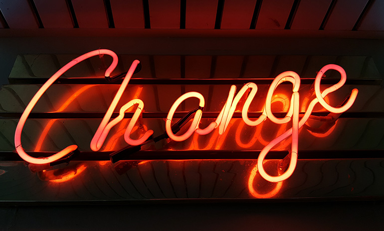 A dark wooden background with a neon orange sign that says 'change'.