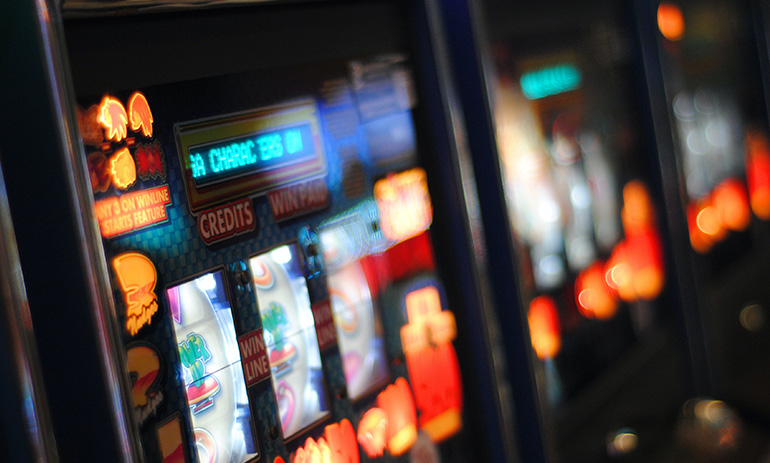 An artistically blurred image of poker machines, showing their colourful screens.
