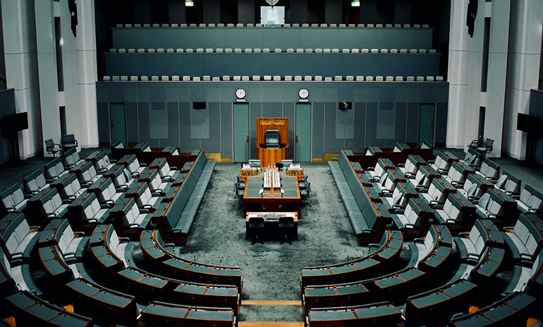 Australia's House of Representatives chamber, showing empty green seats on either side of the speaker's chair.