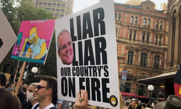 Sign with Scott Morrison's face on it with the words Liar liar our country's on fire, at a climate protest
