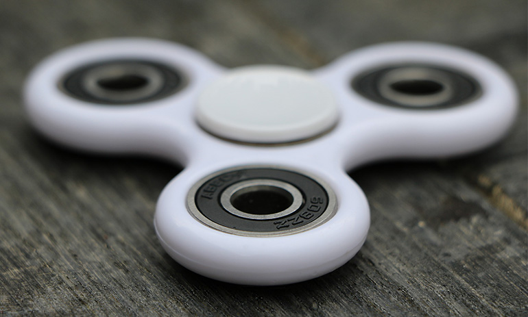 A white fidget spinner on a wooden surface.