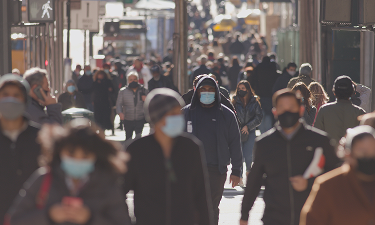 people in the city walking wearing masks