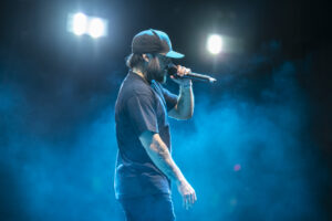 Nooky, an Aboriginal man, singing into a microphone on stage, surrounded by smoke.