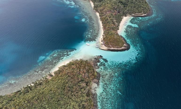 An aerial view of tree-covered islands in a blue sea.