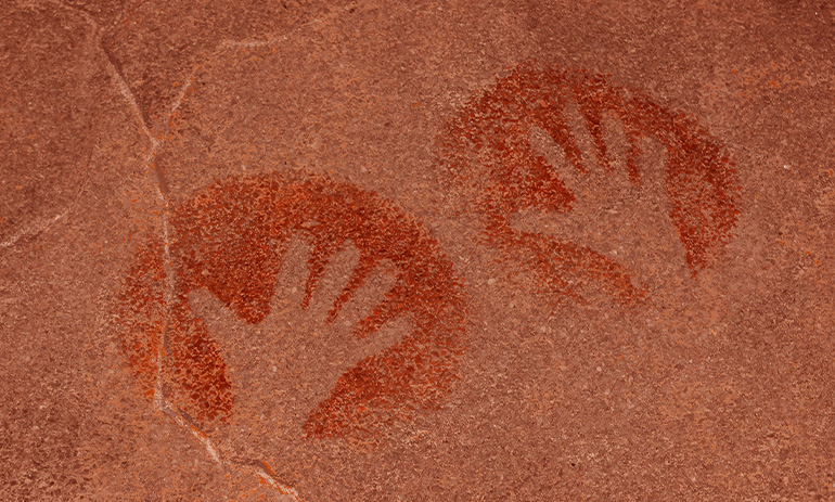 Two handprints made on a red rock