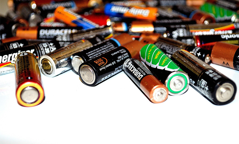 A collection of batteries scattered on a white surface.