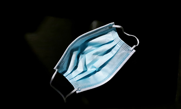 A blue surgical mask against a black background.